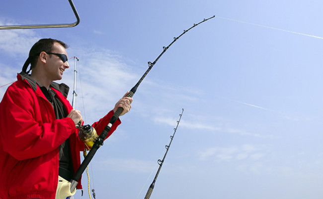 Fisherman fishing on boat big game tuna, blue sunny sky
