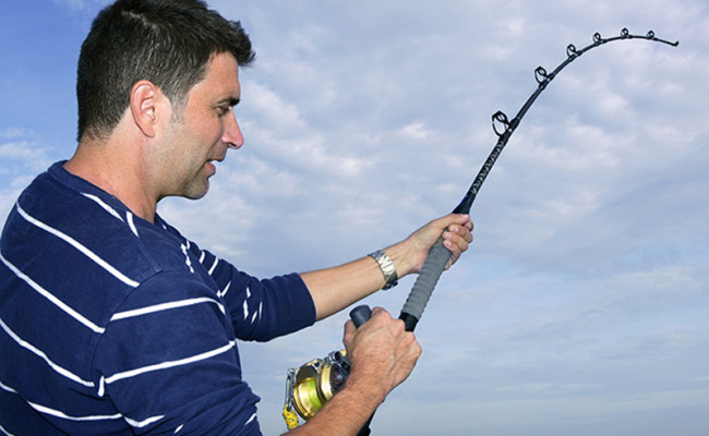Angler fisherman fighting big fish rod and reel